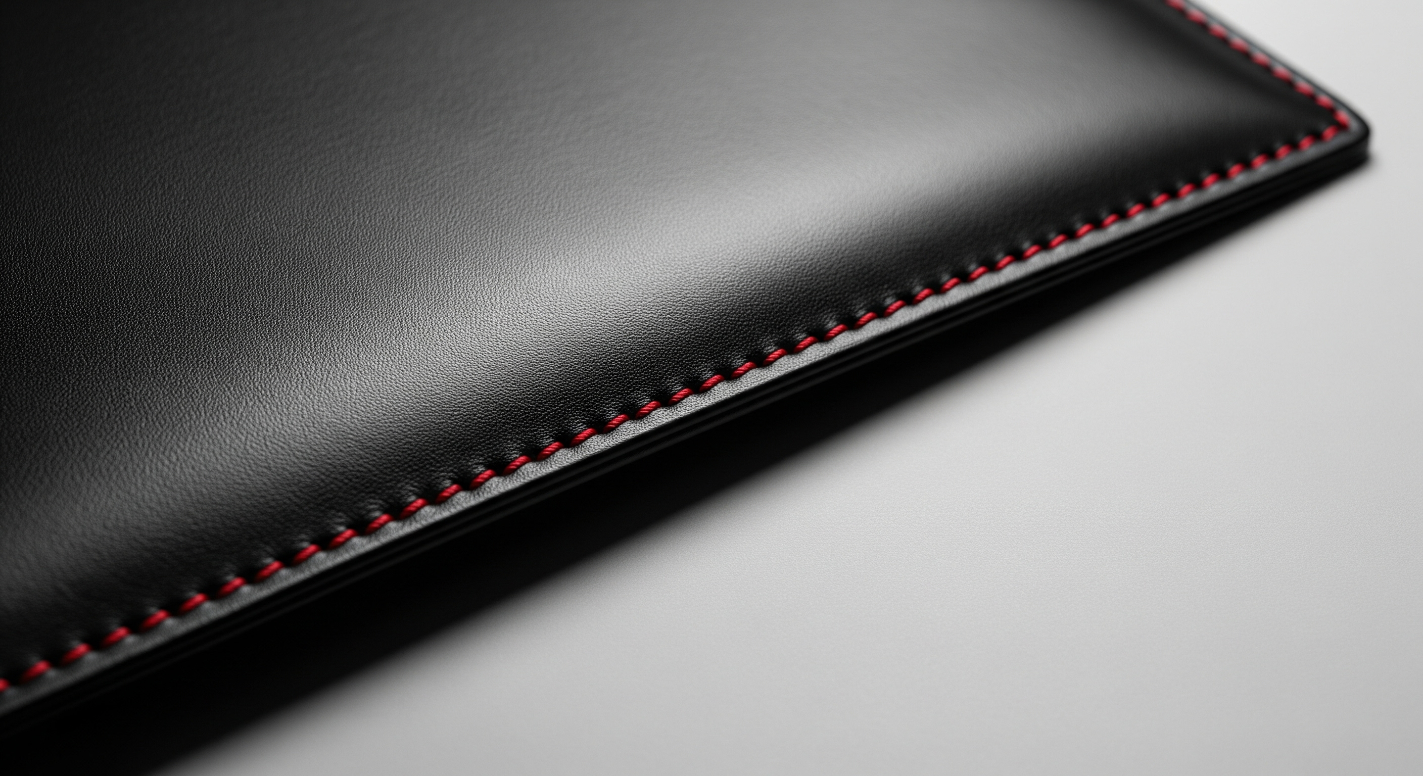Black leather wallet with red stitching on a light gray background